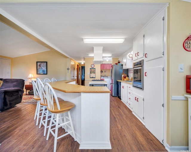 kitchen with white cabinetry, appliances with stainless steel finishes, dark wood-type flooring, and a breakfast bar area