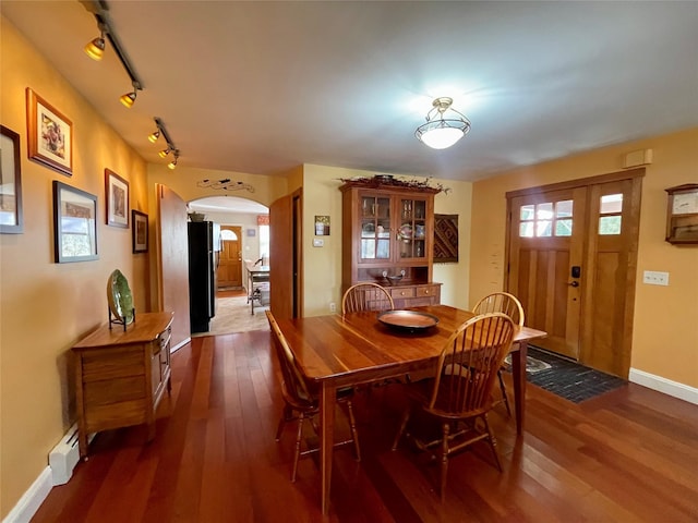 dining room with dark hardwood / wood-style flooring, rail lighting, and baseboard heating