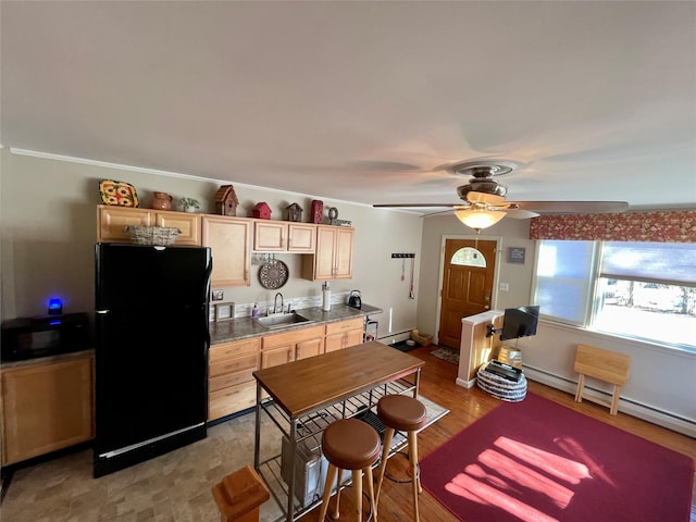 kitchen featuring light brown cabinetry, sink, black appliances, and light wood-type flooring