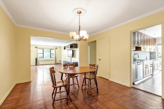 dining area featuring washer / clothes dryer, crown molding, sink, and an inviting chandelier