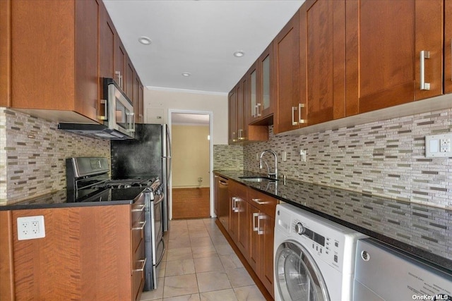 kitchen featuring washer / dryer, sink, dark stone counters, and appliances with stainless steel finishes