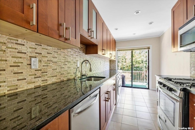 kitchen featuring sink, light tile patterned floors, dark stone countertops, appliances with stainless steel finishes, and backsplash