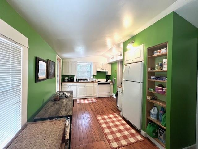 kitchen with hardwood / wood-style flooring, lofted ceiling, white cabinets, and white appliances