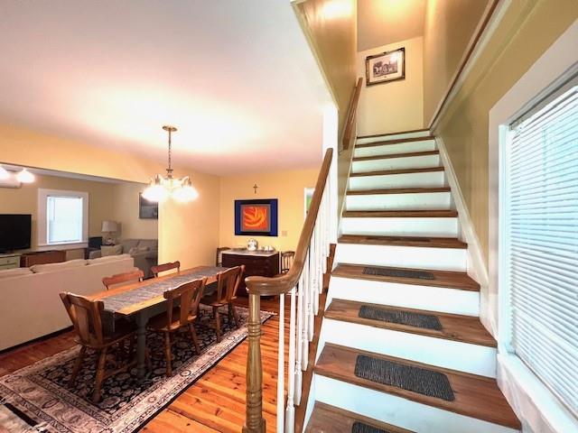 staircase with an inviting chandelier and hardwood / wood-style floors