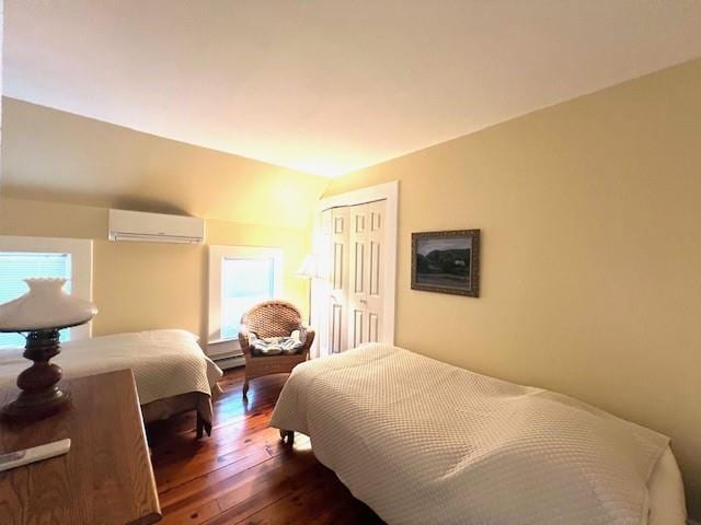 bedroom with dark hardwood / wood-style flooring, lofted ceiling, a wall unit AC, and a closet