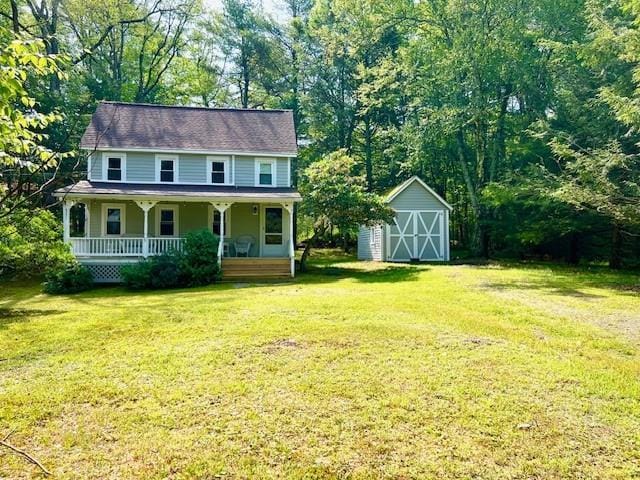 view of front of home with a shed, a front yard, and a porch