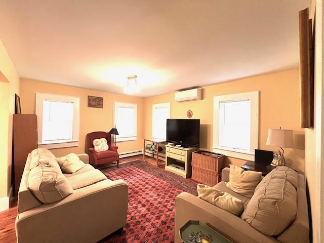 living room featuring baseboard heating and a wall unit AC