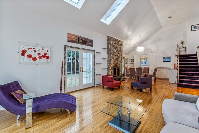 living room featuring a skylight, wood-type flooring, high vaulted ceiling, and french doors