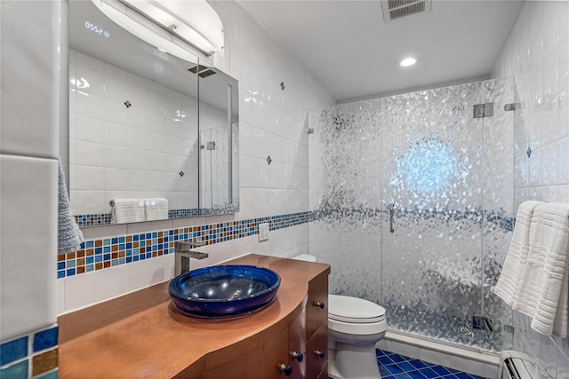 bathroom featuring baseboard heating, tile walls, backsplash, vanity, and walk in shower