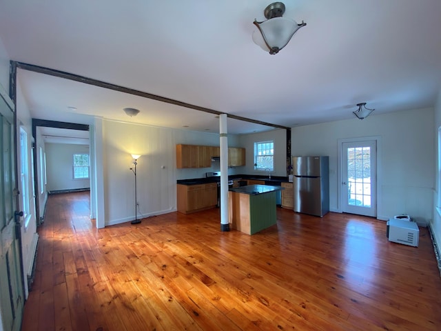 kitchen with a kitchen island, a healthy amount of sunlight, stainless steel fridge, and light hardwood / wood-style flooring