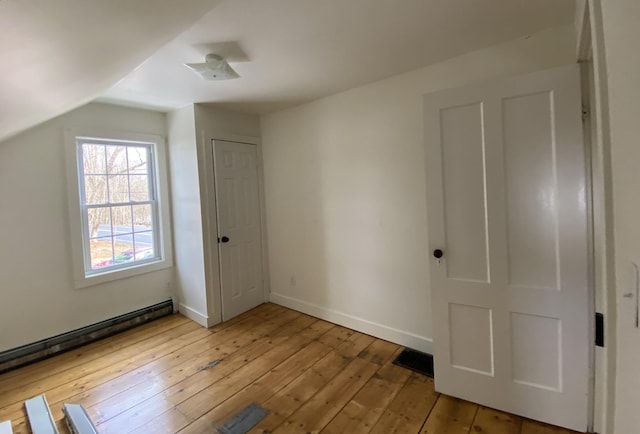 unfurnished bedroom with a baseboard radiator, lofted ceiling, and light hardwood / wood-style flooring