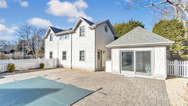 rear view of property featuring a patio and a covered pool