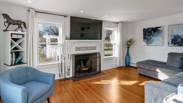 living room featuring a baseboard heating unit, hardwood / wood-style flooring, and plenty of natural light