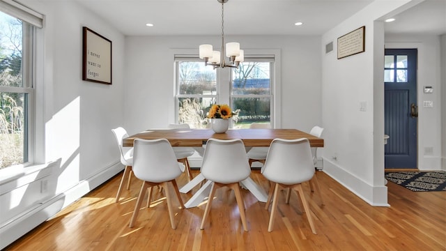 dining space featuring a baseboard radiator, a chandelier, and light hardwood / wood-style floors