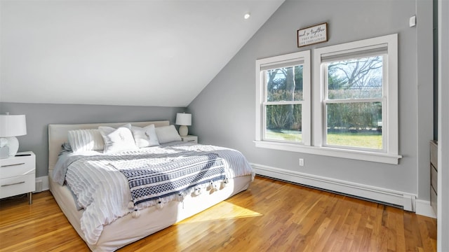 bedroom with lofted ceiling, light wood-type flooring, and baseboard heating