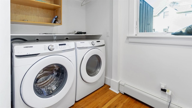 laundry room with light hardwood / wood-style floors, washer and dryer, and a baseboard heating unit