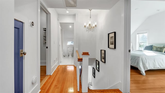 corridor with a notable chandelier and light hardwood / wood-style floors