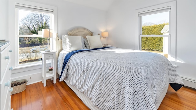 bedroom with hardwood / wood-style floors and a baseboard heating unit