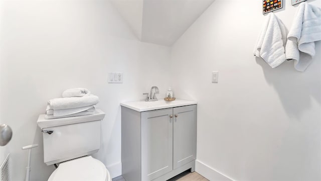 bathroom featuring lofted ceiling, vanity, and toilet