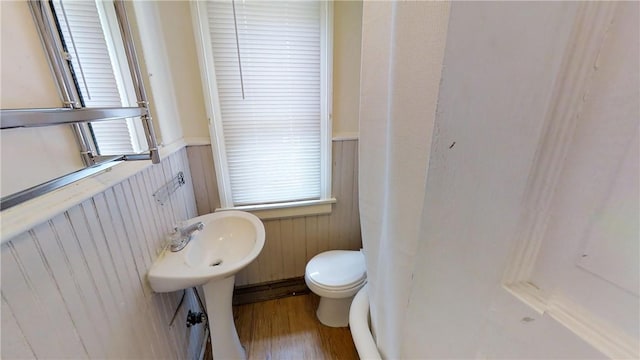 bathroom with hardwood / wood-style flooring, toilet, and wood walls