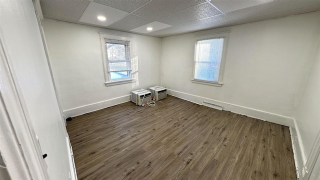 empty room featuring a paneled ceiling and dark hardwood / wood-style flooring