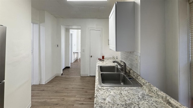 kitchen featuring light stone countertops, sink, and white cabinets