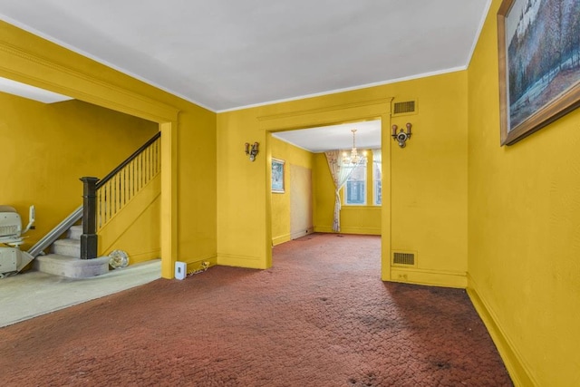 carpeted empty room featuring an inviting chandelier and crown molding