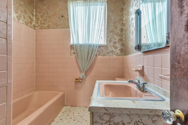 bathroom with sink, a bath, tile patterned floors, and tile walls