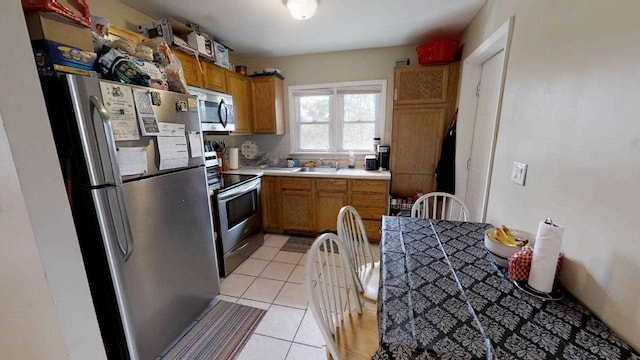 kitchen featuring light tile patterned floors, stainless steel appliances, and sink