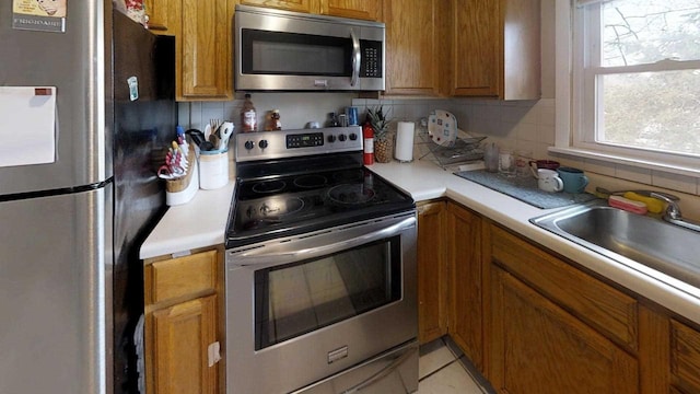 kitchen with stainless steel appliances, sink, decorative backsplash, and light tile patterned floors