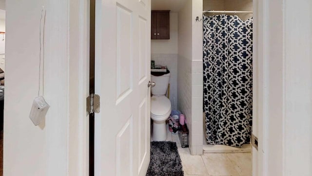 bathroom with tile patterned flooring, tile walls, a shower with shower curtain, and toilet