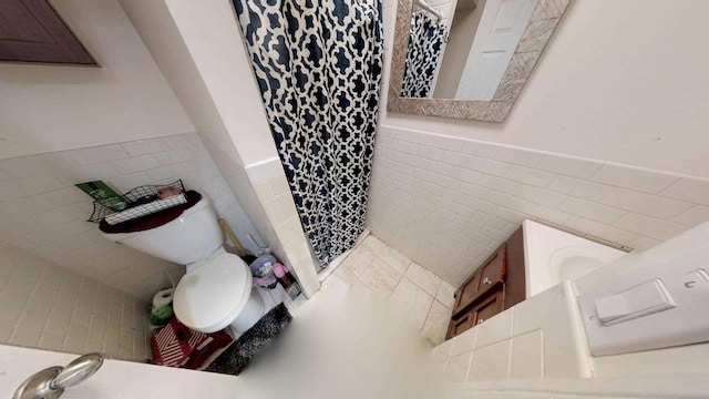 bathroom with tile walls, toilet, and a tile shower