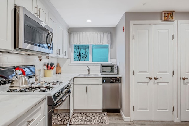 kitchen with white cabinetry, sink, light stone counters, and stainless steel appliances