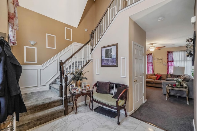 entryway with a towering ceiling and ceiling fan