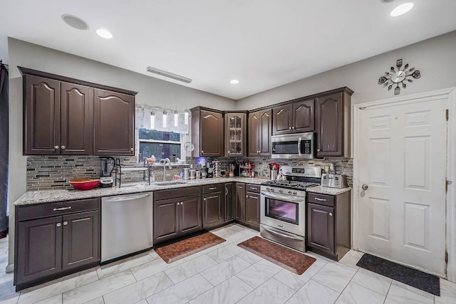 kitchen featuring dark brown cabinetry, sink, backsplash, and appliances with stainless steel finishes