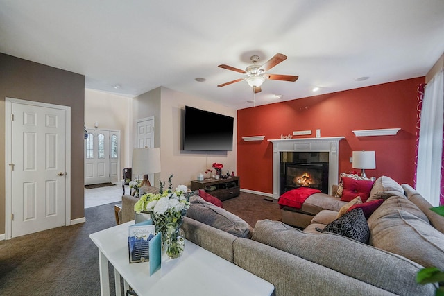 living room featuring a tiled fireplace, dark colored carpet, and ceiling fan