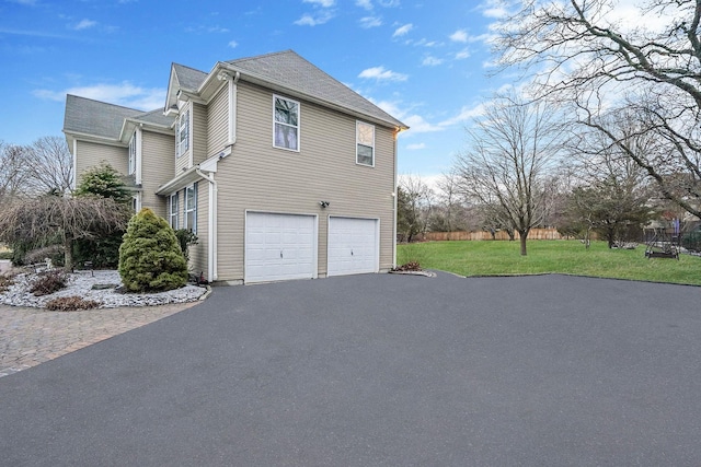 view of side of home featuring a garage and a lawn