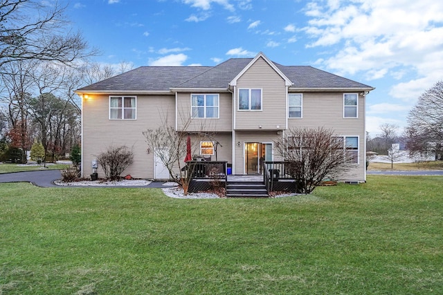 back of property featuring a deck and a lawn