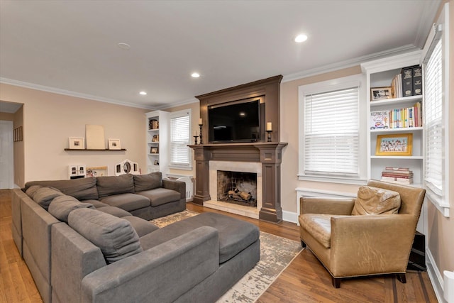 living room featuring hardwood / wood-style flooring, a premium fireplace, and crown molding