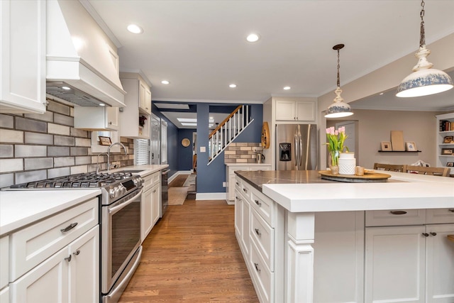 kitchen featuring hanging light fixtures, stainless steel appliances, custom range hood, and a kitchen island