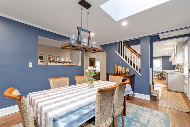 dining room with hardwood / wood-style flooring, ornamental molding, and a skylight