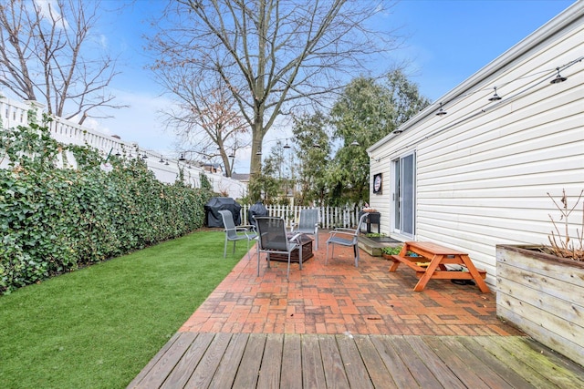 wooden deck with a patio and a lawn