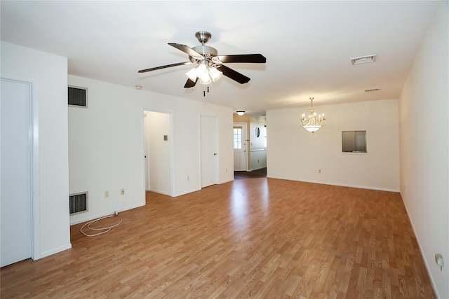 empty room featuring ceiling fan with notable chandelier and light hardwood / wood-style floors