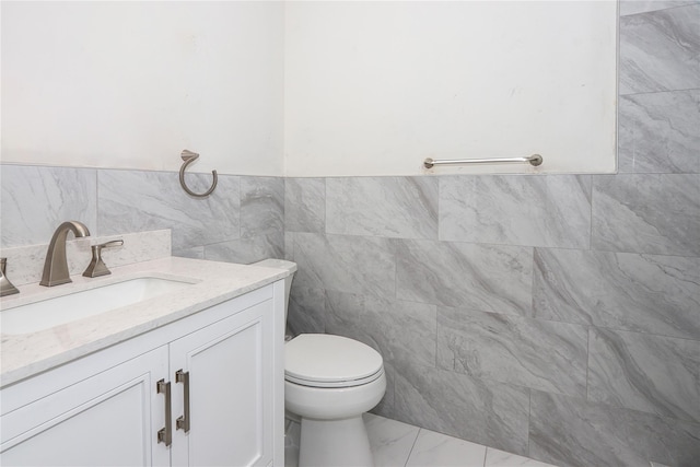 bathroom with vanity, tile walls, and toilet