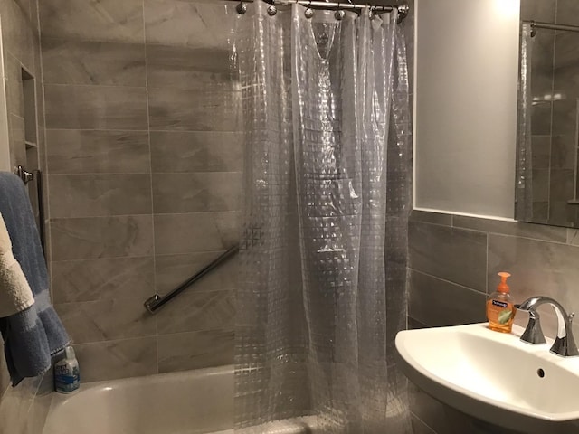 bathroom featuring shower / bath combination with curtain, sink, and tile walls