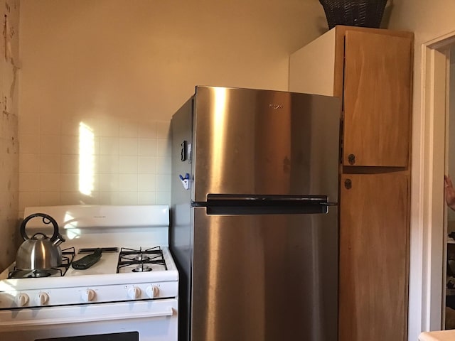 kitchen with stainless steel fridge and white range with gas stovetop