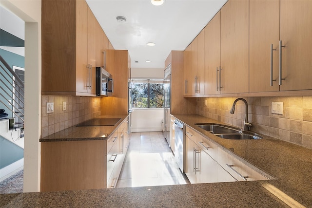 kitchen featuring sink, light tile patterned floors, appliances with stainless steel finishes, dark stone counters, and decorative backsplash