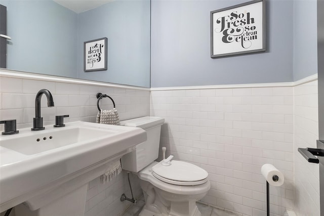 bathroom featuring tile walls and toilet