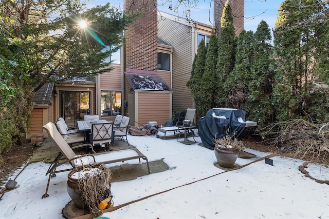 snow covered patio with area for grilling and an outdoor fire pit