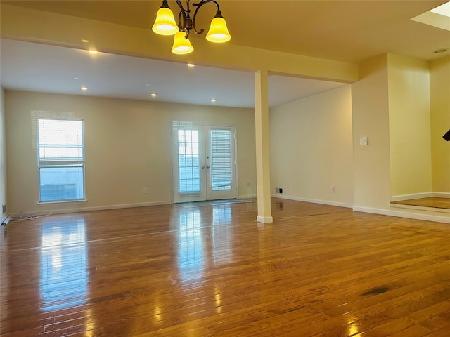 empty room with wood-type flooring, french doors, and a chandelier